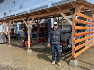 Owner Travis Morson standing by stained cedar pavilion with metal roof